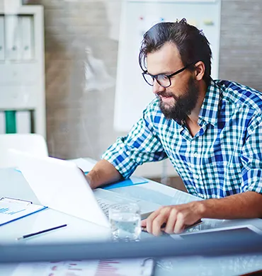 imagen de un colaborador sonriendo mirando su laptop